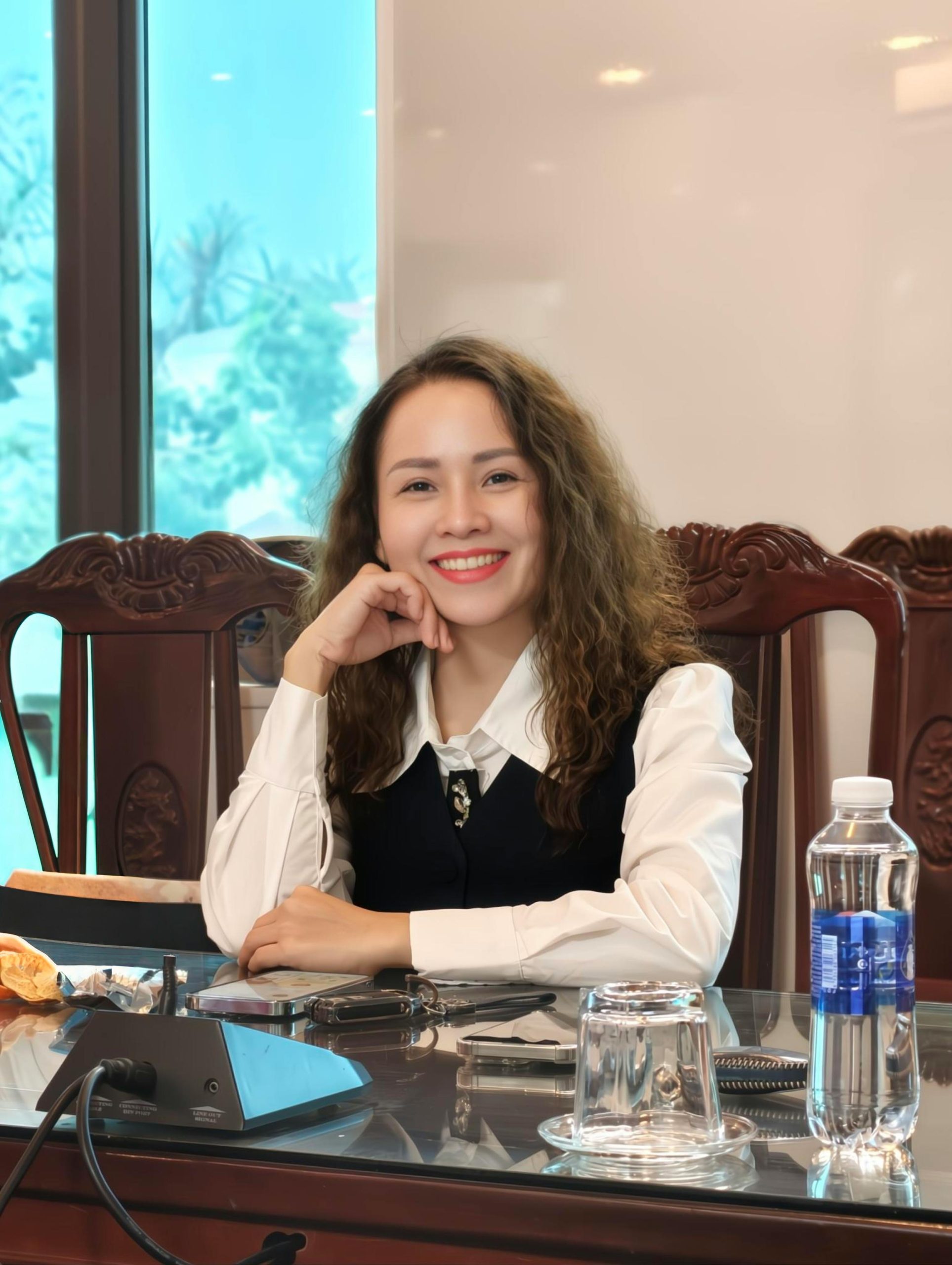 Confident professional woman smiling at a desk with office supplies.