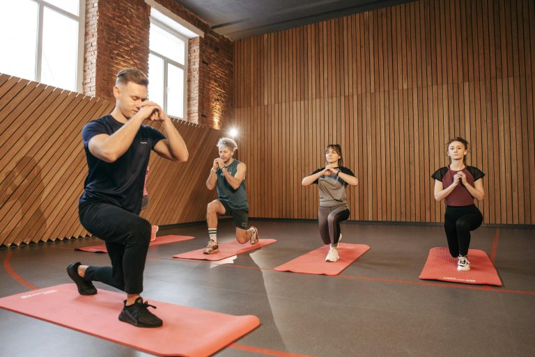 Home Adults practicing exercises on yoga mats in a contemporary studio setting.
